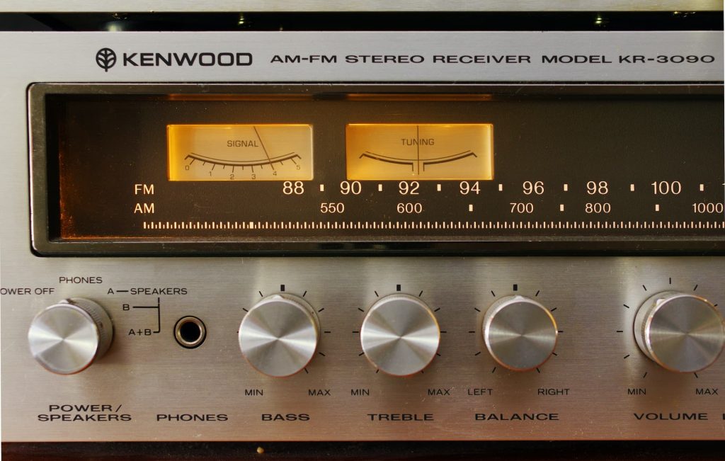 Close-up of a Kenwood AM-FM stereo receiver, model KR-3090, featuring two analog dials for signal and tuning, and six silver knobs for power, speakers, bass, treble, balance, and volume control. Perfect for those considering electronic recycling in Atlanta GA. Buttons and frequency scale are also visible.