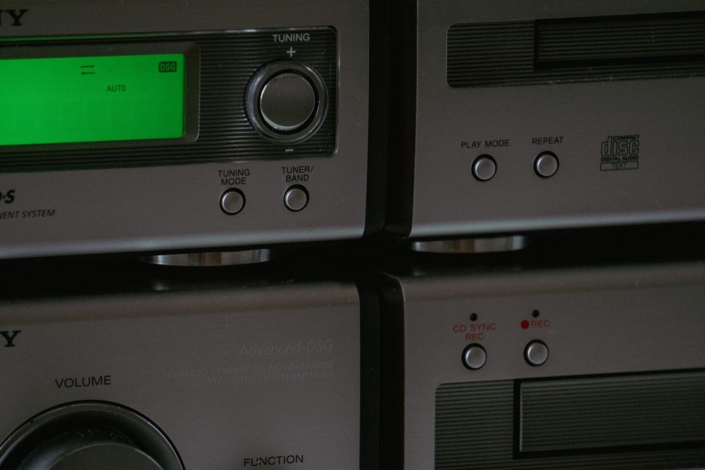 Close-up view of a vintage audio system with a green digital display showing "AUTO." Buttons for tuning, volume, play mode, and function are visible, along with a CD sync and recording feature. The metallic finish makes this an ideal candidate for electronic recycling in Atlanta GA.