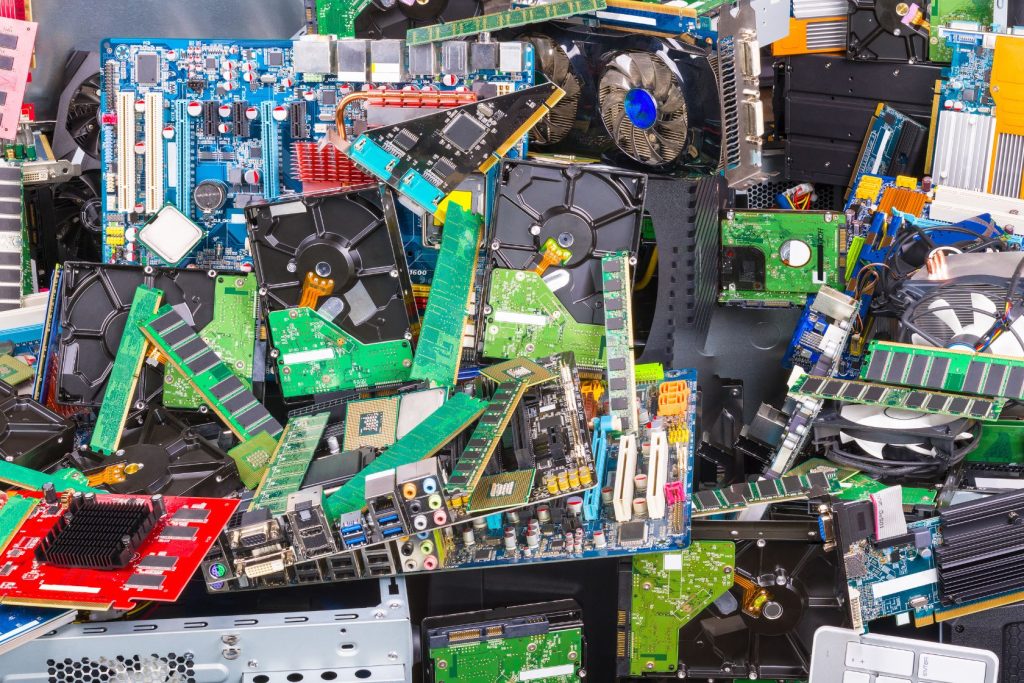 A chaotic heap of various computer components, including circuit boards, graphics cards, and cooling fans. This electronic waste in Atlanta GA is stacked haphazardly, showcasing an array of green, red, and blue circuit boards with visible connectors and chips.