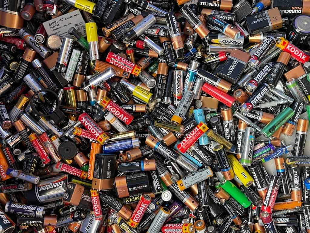 A large pile of assorted used batteries, including AA, AAA, C, and D sizes from brands like Duracell and Energizer. Scattered closely together in vivid colors and labels, they await a sustainable future at the Electronic Recycling Drop Off Box in Atlanta, GA.