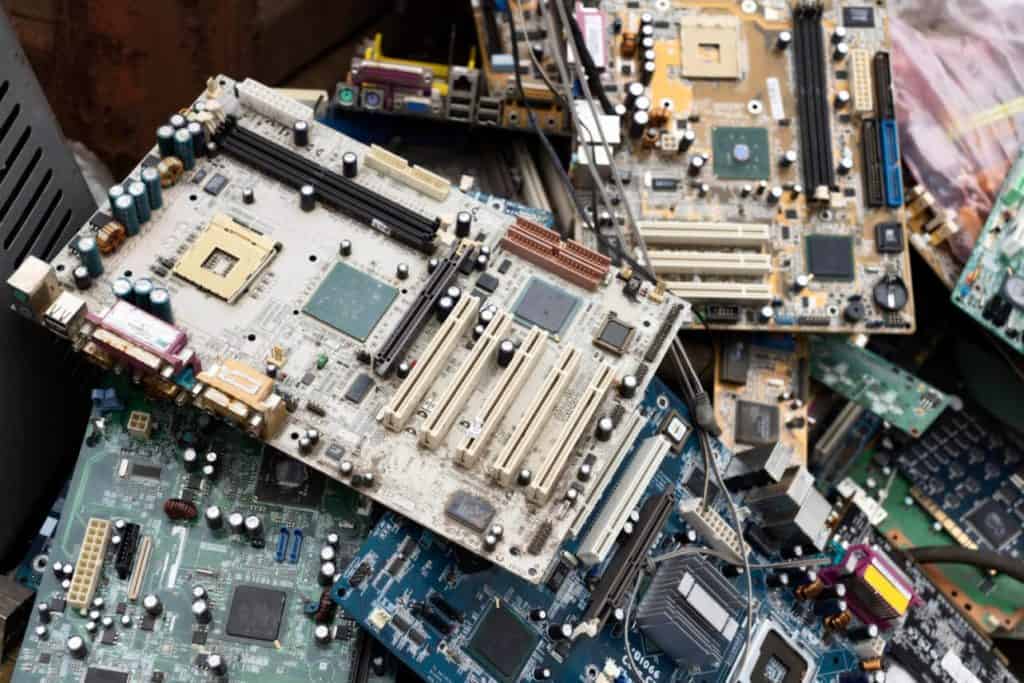 A pile of discarded electronic circuit boards, including various motherboards with visible slots and components, is stacked haphazardly. The different colors and sizes symbolize the mixed electronic waste often tackled by Electronic Recycling Atlanta GA.