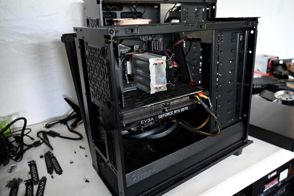 An open black computer case on a desk, partially assembled with a visible EVGA GeForce RTX 2070 graphics card and CPU cooler, hints at an electronics project underway. Wires are loosely placed inside, while various computer parts and tools are scattered nearby—evoking a scene from Electronics Atlanta GA.