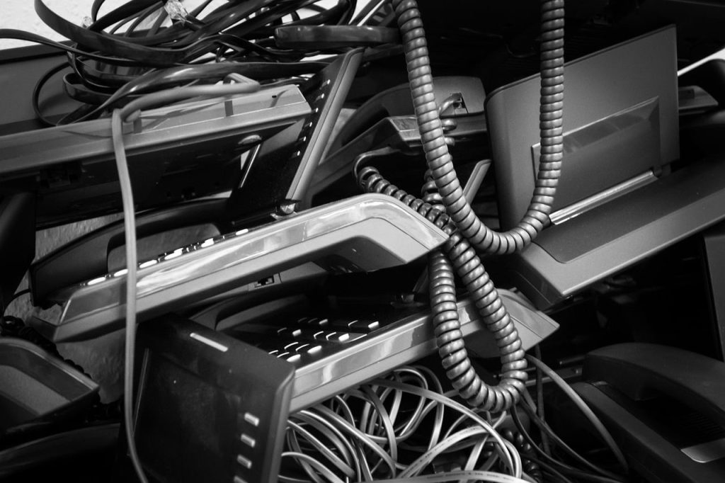 A cluttered pile of electronic waste in black and white showcases a chaotic tangle of cables and monitors, highlighting the need for electronic recycling in Atlanta, GA.