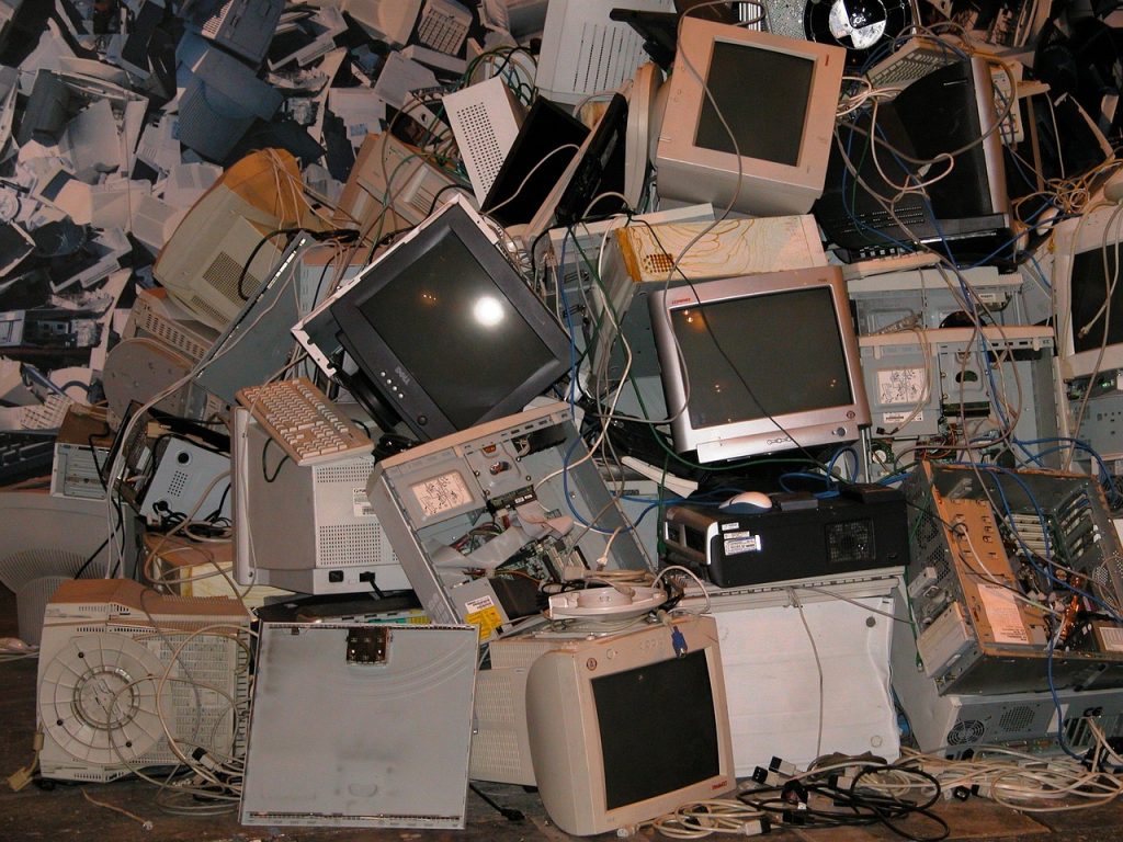 A large pile of old, discarded computer monitors, towers, and cables stacked haphazardly. The image depicts electronic waste in need of processing at an Electronic Recycling drop-off box in Atlanta, GA, highlighting outdated technology and recycling issues.