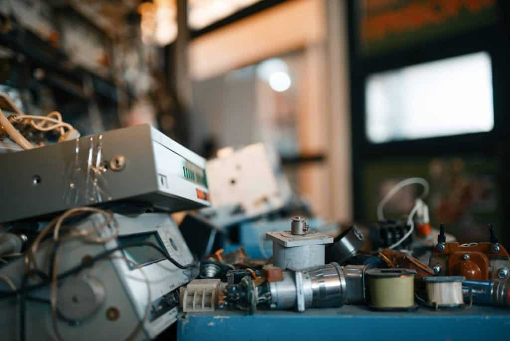 A cluttered workspace in Electronics Recycling Atlanta GA, filled with various components like circuit boards, wires, and devices. The focus is on a jumble of parts on a table, hinting at the bustling activity of an electronics repair shop in the heart of the city.