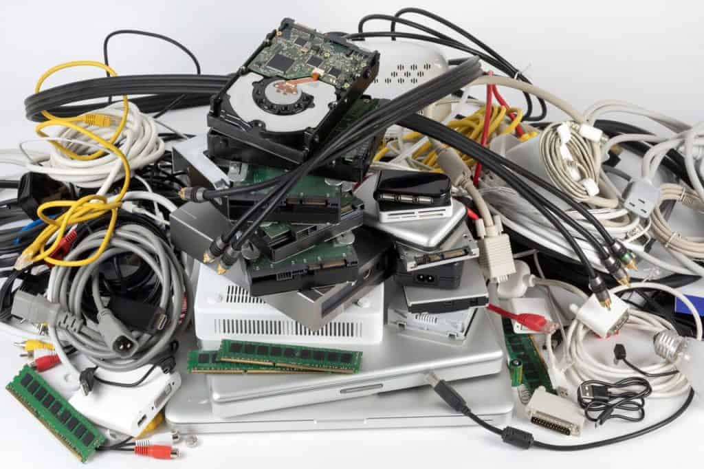 A jumble of electronic components and cables, such as hard drives, circuit boards, RAM sticks, and various cords and connectors, all piled up against a plain background, ready for Electronic Recycling in Atlanta GA.