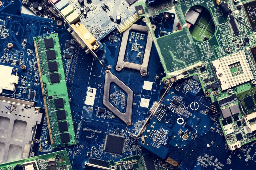 A vibrant assortment of computer circuit boards and electronic components, featuring green and blue hues, showcases the dynamic world of electronics in Atlanta, GA. Various chips, capacitors, and connectors are visible in a jumbled arrangement ready for electronic recycling.