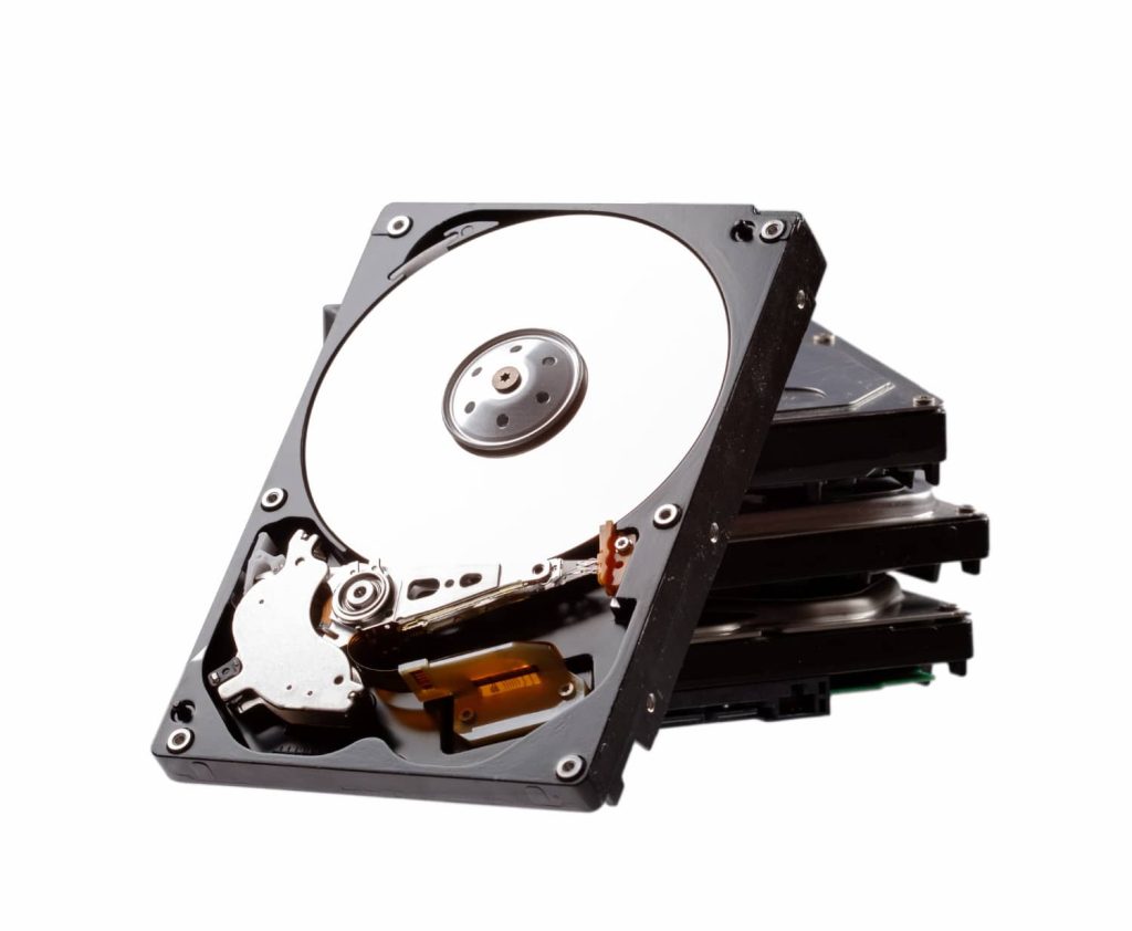 A stack of opened hard disk drives is shown against a white background, emphasizing electronic recycling opportunities in Atlanta, GA. The top drive displays its internal components, including the silver platters and read/write arm.